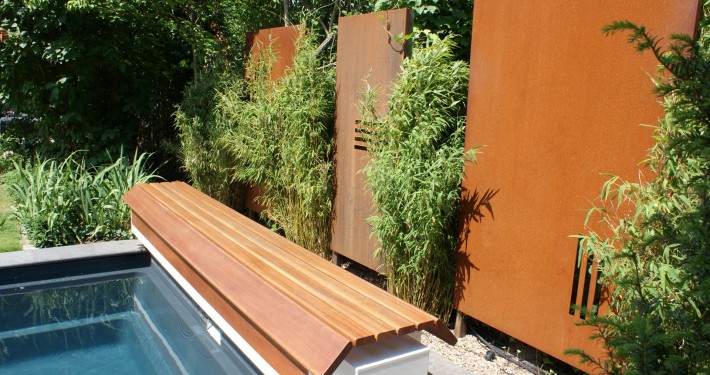 Cortenstahl-Wand als Sichtachse am Ende des Pool mit Bambuspflanzen