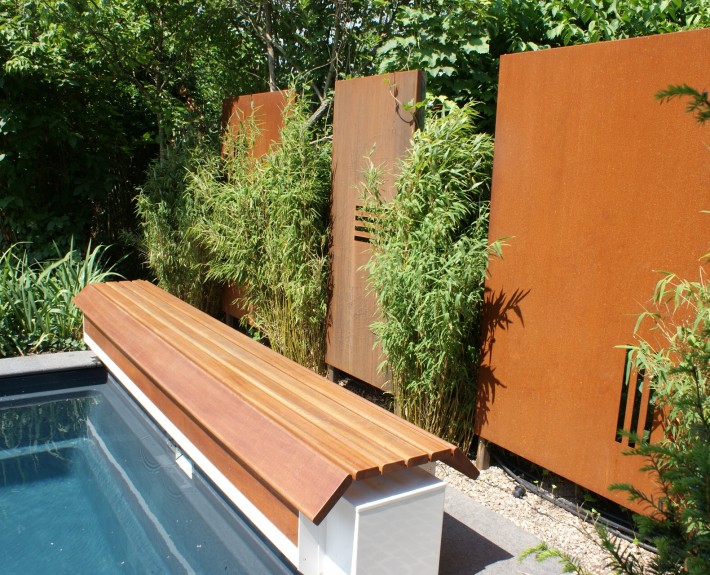 Cortenstahl-Wand als Sichtachse am Ende des Pool mit Bambuspflanzen